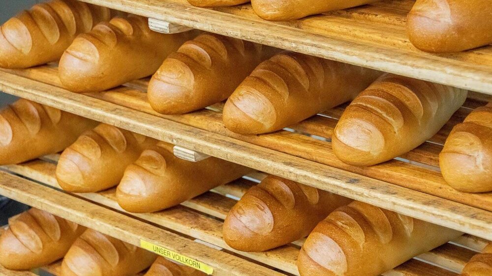 Frische Brotlaibe direkt aus dem Ofen liegen in einem Holzregal