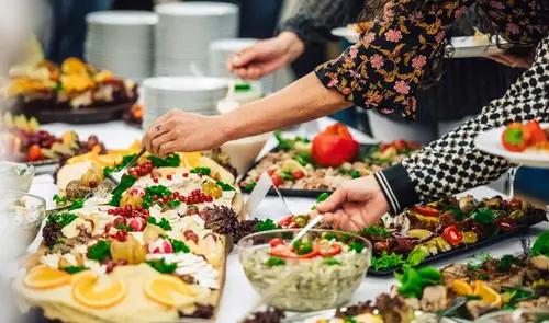 Mehrere Menschen bedienen sich bei einem Buffet der Züssower Service und Catering