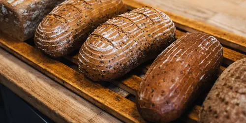 Frisch gebackene Laibe Vollkornbrot liegen auf einer Holzauslage