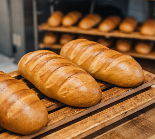 Mehrere Laibe Weißbrot liegen in einer Auslage neben dem Backofen