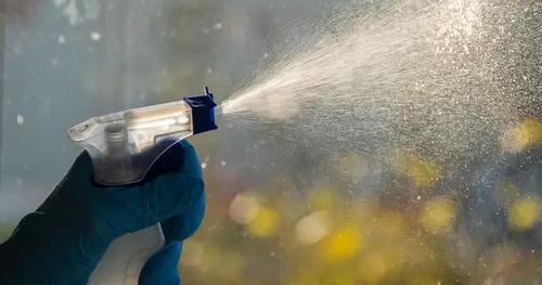 Ein Glasreinigungsspray wird auf eine Glasfassade aufgetragen und geputzt