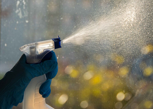 Ein Glasreinigungsspray wird auf eine Glasfassade aufgetragen und geputzt