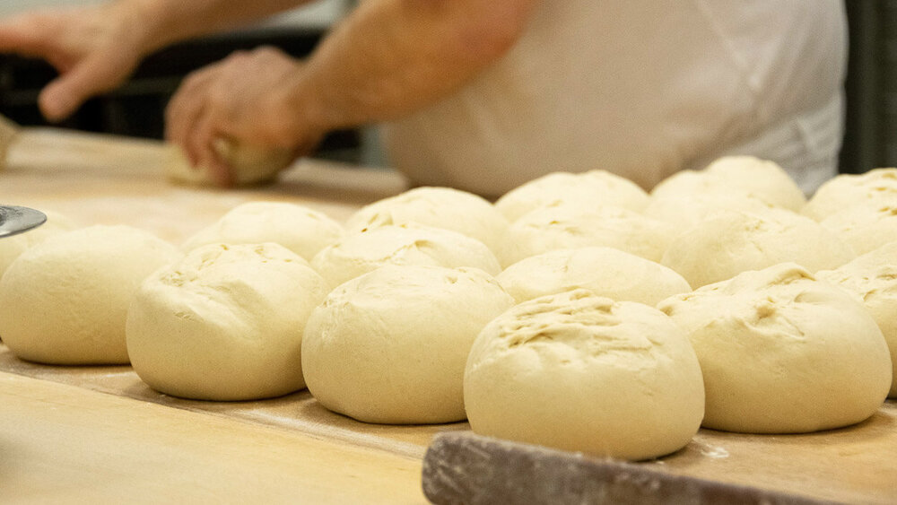Ein Stapel frischer Brötchen, die noch nicht gebacken sind, liegt auf einer Theke
